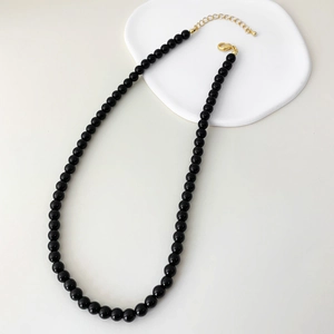 Detail of minimalist black agate beaded necklace with gold lobster clasp and extension chain