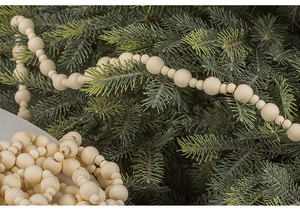 Close-up of wooden bead garland hanging on pine branches for festive DIY home decor