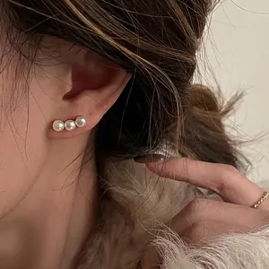 Elegant silver pearl stud earrings with three pearls worn on a model for a chic look