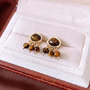 Vintage oval tiger eye stone beaded earrings with gold metallic finish on velvet