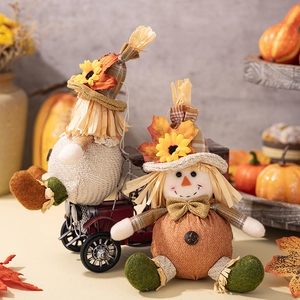Detail view of two handcrafted straw scarecrow dolls with autumn maple leaves and pumpkins