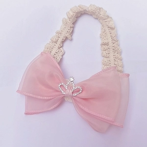 Close-up of pink lace baby headband with a delicate bow and rhinestone crown detail