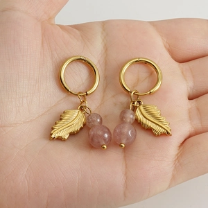 Golden leaf hoop earrings with strawberry quartz stone beads held in hand for scale