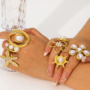 Golden ocean-style ring set with starfish and pearls displayed on a hand with a glass
