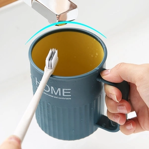 Two-tone blue and yellow mouthwash cup with handle held under a water tap