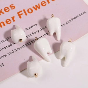 Macro view of five 3D white resin tooth charms with gold rings for DIY jewelry