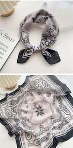 Detail of square silk scarf showing black and white paisley pattern with chain elements
