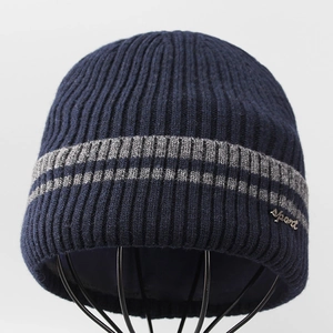 Detailed knit texture of dark blue wool beanie with sport metal tag and grey stripes