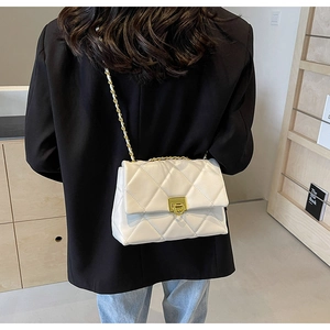 White quilted crossbody bag with gold chain strap worn over a black blazer jacket