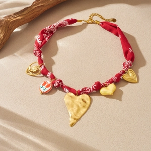 Red printed ribbon necklace with gold heart charms and floral ceramic pendant
