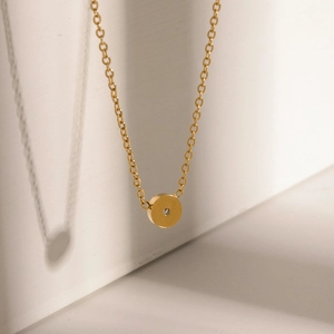 Detailed view of a gold titanium steel necklace featuring a zircon-inlaid round pendant