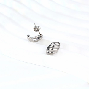 Silver croissant dome stud earrings with ribbed texture on a white display stand