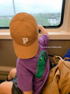 Kids baseball cap with P embroidery shown with a purple dinosaur t-shirt and khaki backpack