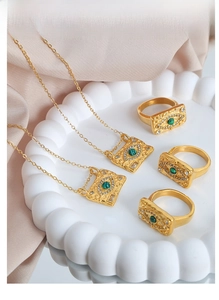 Detailed close-up of vintage gold evil eye jewelry set with green gems on silk