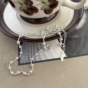 Detail of S925 sterling silver beaded necklace draped on a vintage coffee cup