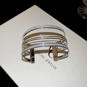 Detail of silver multi-layer open cuff bracelet with polished and glittery metal finish