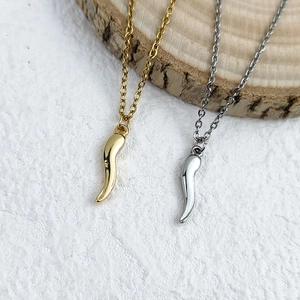 Polished gold and silver chili pepper necklaces on wood and marble backdrop