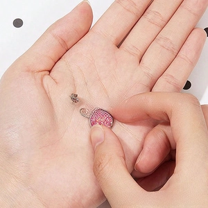 Detailed macro view of pink glitter stud earring held by hand to show size and texture