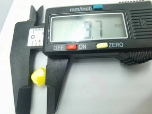 Detailed measurement of a 9.7 mm yellow ceramic shell bead using a digital caliper