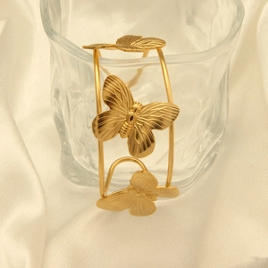 Detailed view of 18k gold butterfly bangle on white silk with soft lighting