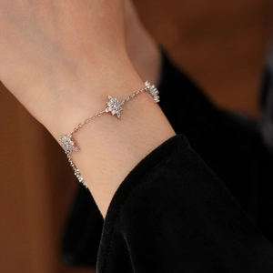 Gros plan d'un bracelet argenté avec pendentif étoile en zircon porté sur un poignet