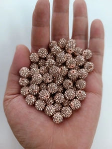 Close-up of 10mm rose gold Shamballa beads with rhinestones held in hand for scale