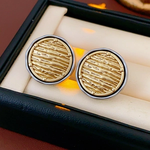 Macro shot of two-tone gold and silver round earrings with textured surface in a jewelry box