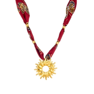 Detail view of gold sun pendant necklace with elegant dark red floral silk ribbon strap