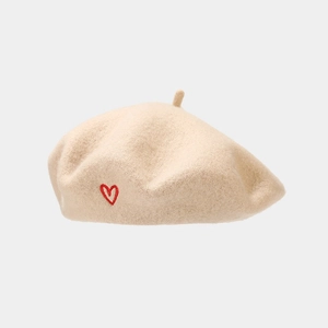 Close-up of heart embroidery detail on a cream wool beret for a vintage aesthetic