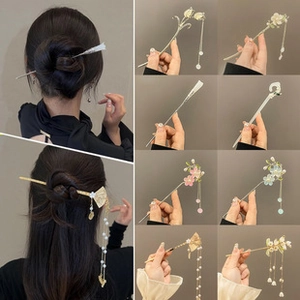Detailed close-up of various vintage-style gold hairpins with floral resin charms and tassels
