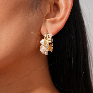 Elegant gold flower cluster earrings with pearls and crystals on a female model