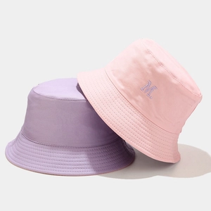 Dettaglio di cappelli a secchiello rosa e viola con ricamo della lettera M in rilievo