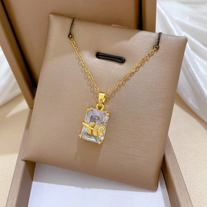 Macro detail of gold rectangle leaf pendant with sparkling zircons on silk background