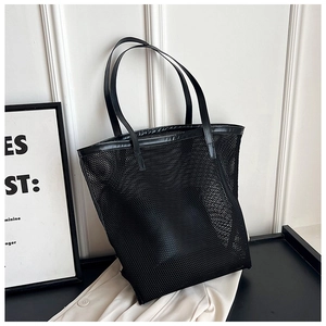Detail of black mesh beach tote bag featuring durable PU leather handles on a desk