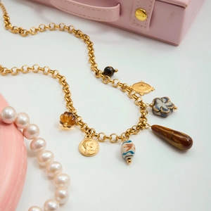 Détail macro du collier rétro doré avec fleurs vintage en œil de tigre et pendentif pièce