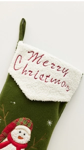 Detailed view of dark green Christmas stocking with white cuff and snowman embroidery