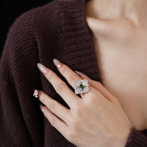 Detailed view of flower ring featuring a green square crystal and clear zircons