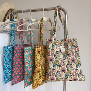 Detail of vintage floral canvas tote bags in four patterns hanging on a metal rack
