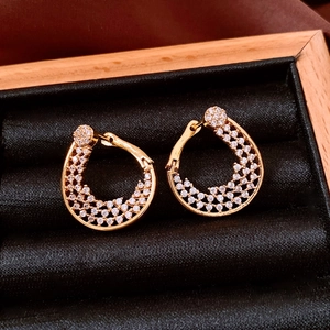 Detailed top view of gold flower-twist hoop earrings with cubic zirconia on black velvet