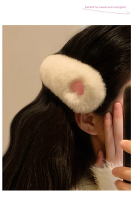 Detail of plush faux rabbit fur hair clip with a pink heart on a model's hair