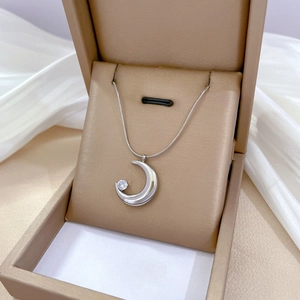 Macro shot of silver crescent moon pendant with round zircon on a sleek snake chain