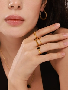 Close-up of model wearing gold chain rings with black rectangular onyx inlay details