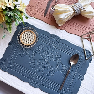 Detailed close-up of embossed floral patterns on blue and pink faux leather placemats