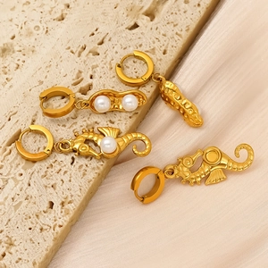 Golden seahorse and peanut stud earrings with pearls on silk and stone background