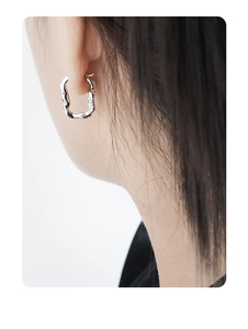 Detailed view of irregular U-shaped silver earring with S925 hallmark on female model