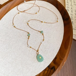 Détail du collier de perles avec pendentif étoile en pierre verte sur cordon tressé