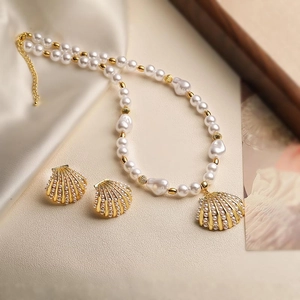 Detail of seashell jewelry set with pearl necklace and gold earrings on silk background