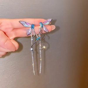 Détail de boucles d'oreilles papillon asymétriques avec dégradé et longues chaînes à glands