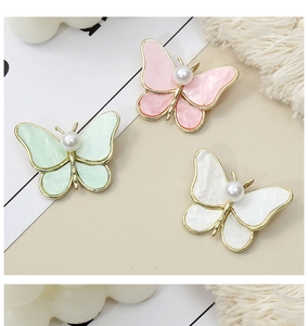 Detail of butterfly brooches in pastel colors with marble texture and pearl accents