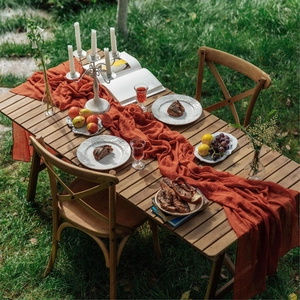Terracotta cheesecloth table runner on outdoor dining setup with candles and snacks